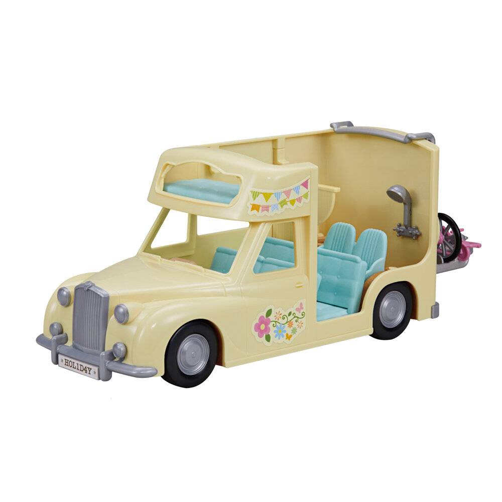 Vintage gelber Spielzeug-Wohnwagen mit blauen Sitzen und Blumendekoren, dargestellt auf weißem Hintergrund.