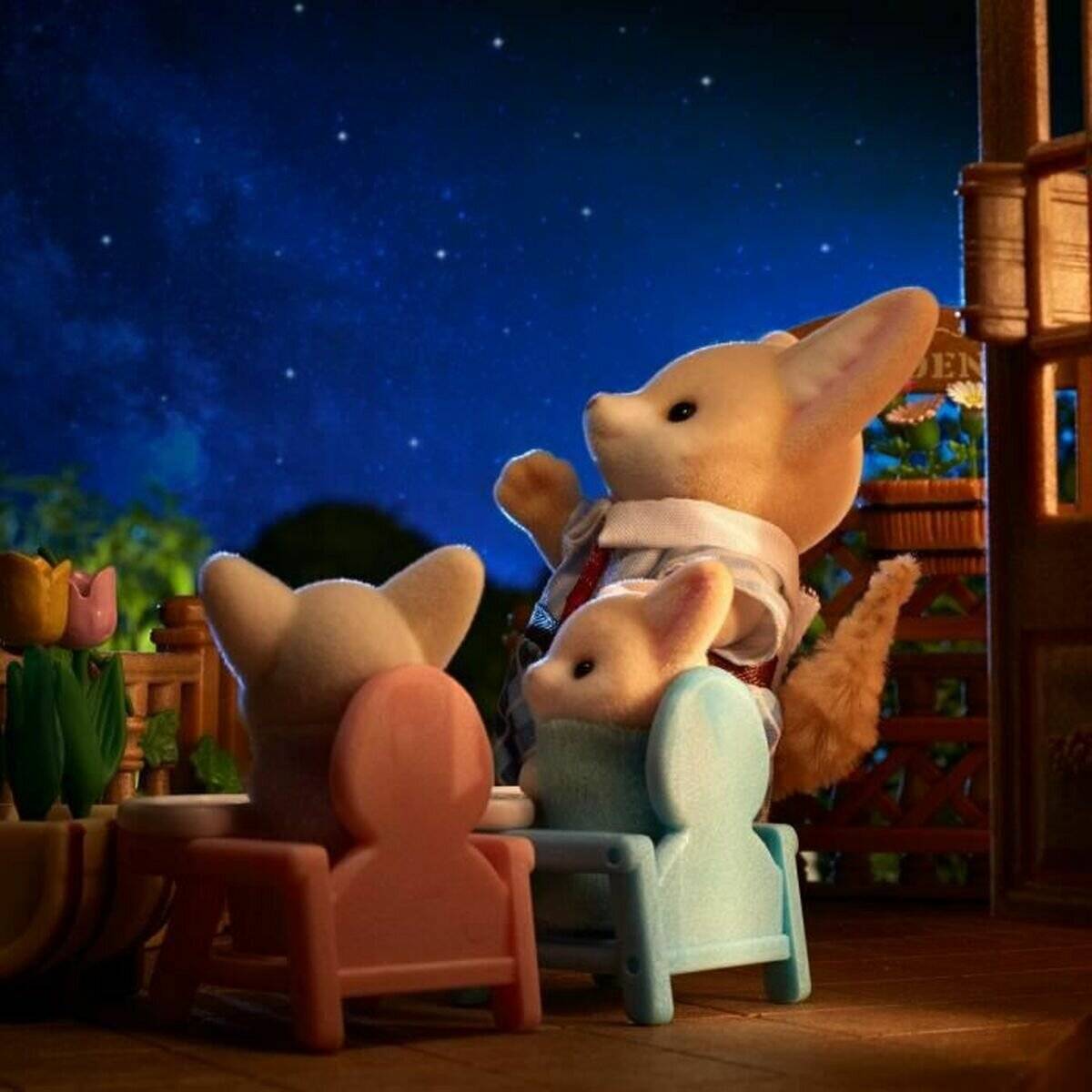 Drei Spielzeugkaninchen sitzen auf Stühlen und beobachten eine weiße Kaninchenfigur, die auf einer Holzterrasse in der Nacht unter einem Sternenhimmel steht und gestikuliert.
