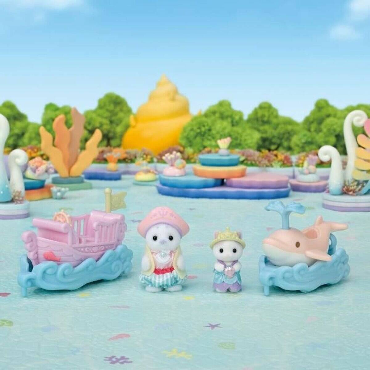 Pastellfarbene Spielzeug-MeeresSzene mit zwei kleinen Tierfiguren zwischen einer rosa Kutsche und einem blauen Wal, mit goldenem muschelförmigem Hintergrund und bunten Plattformen.