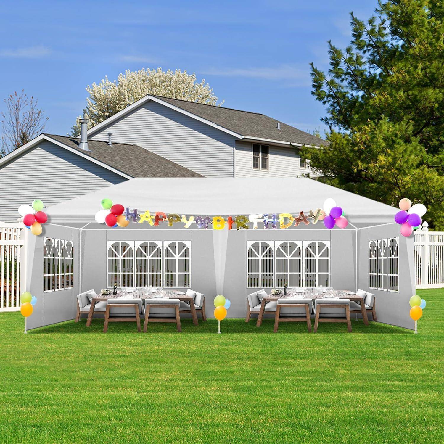 Geburtstagszelt im Hinterhof mit "Alles Gute zum Geburtstag""-Banner, Luftballons und für Gäste eingedeckten Tischen auf dem Rasen.