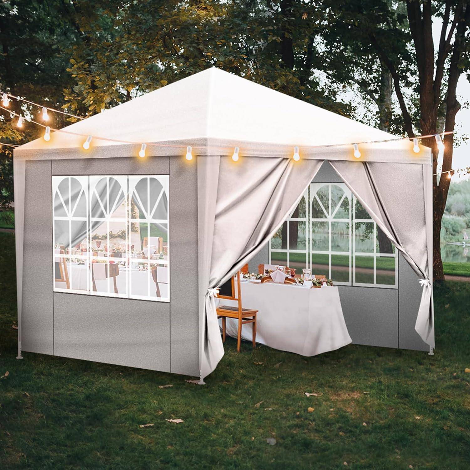 Outdoor-Veranstaltungszelt mit weißem Dach, Gardinen-Eingang und Lichterketten auf Gras neben Tischen und Stühlen aufgebaut.