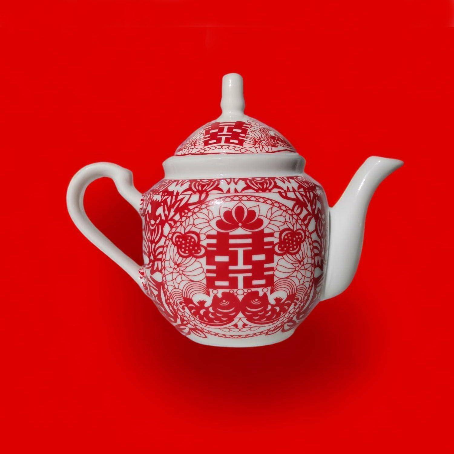 Weiße Teekanne mit roten floralen und geometrischen Mustern auf rotem Hintergrund.