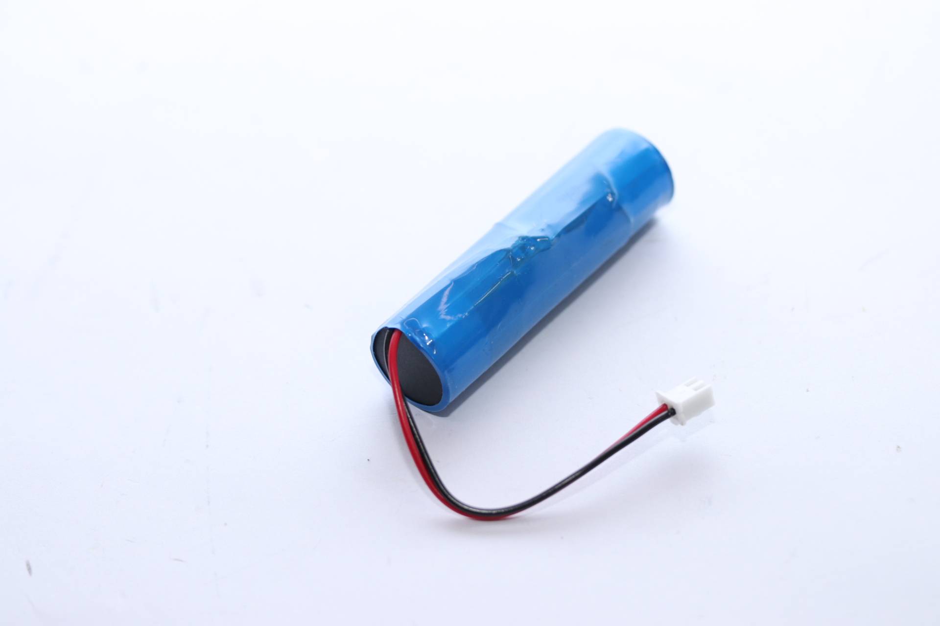 Blaues zylindrisches Batteriepack mit roten und schwarzen Drähten, die an einem weißen Stecker auf weißem Hintergrund enden