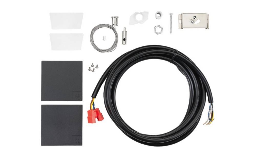 Elektrozubehör-Set: Aufgerolltes schwarzes Kabel mit roten Steckern, zwei dunkle Paneele, transparente Abdeckungen und verschiedene Befestigungsteile auf weißem Untergrund.