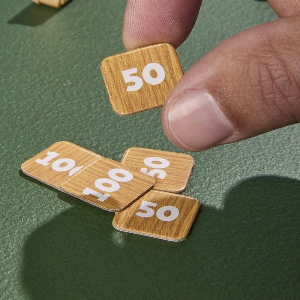 Eine Hand legt eine kleine Holzplatte mit der Aufschrift „50