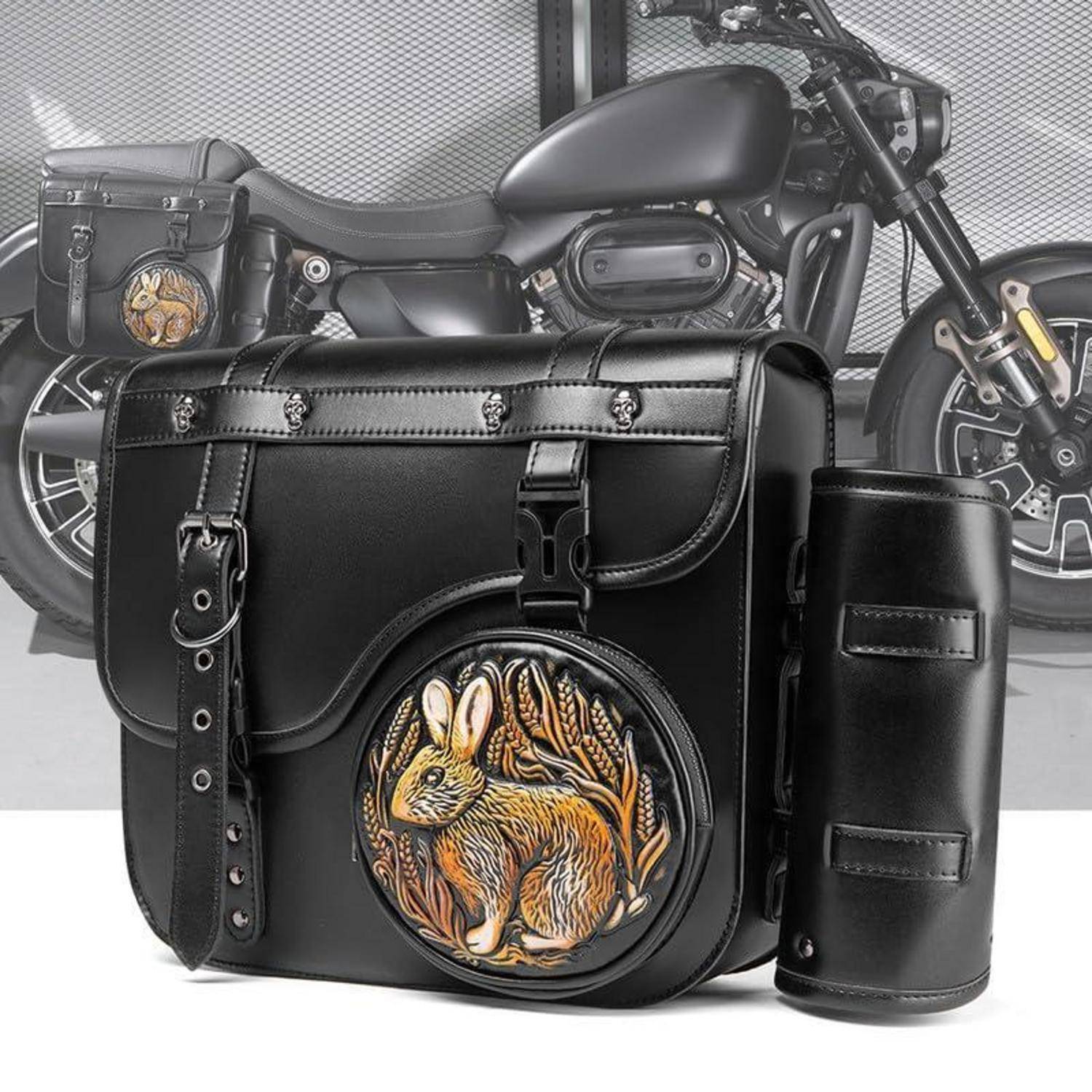Schwarze Ledermotorrad-Satteltaschen und matching Zylindertasche mit rundem Kaninchen-Emblem, gezeigt vor einem Motorrad.