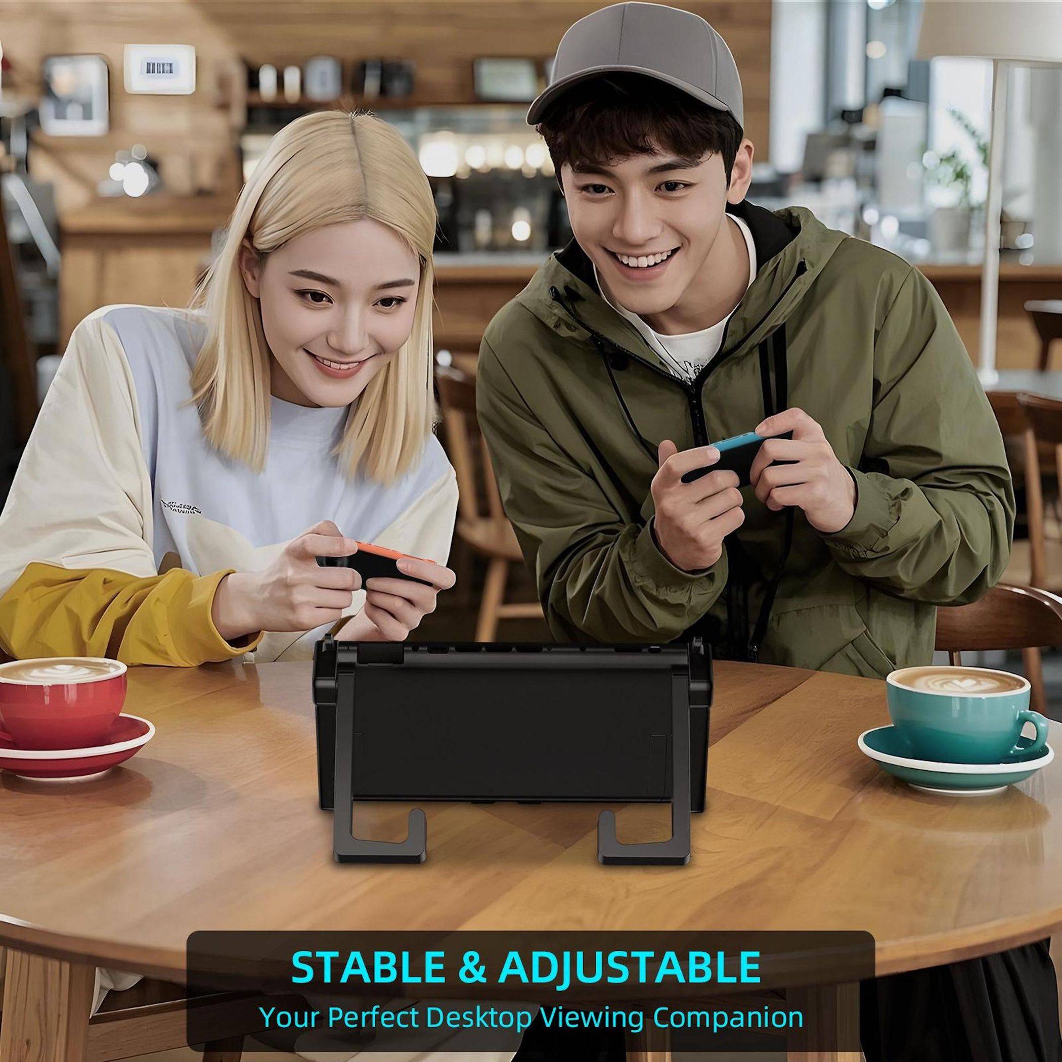 Junges lachendes Paar spielt an einem Café-Tisch mit einem tragbaren Spielgerät, während es ein Tablet auf einem Ständer betrachtet, auf dem Text zu sehen ist: „STABIL & VERSTELLBAR Dein perfekter Desktop-Begleiter für optimales Betrachten