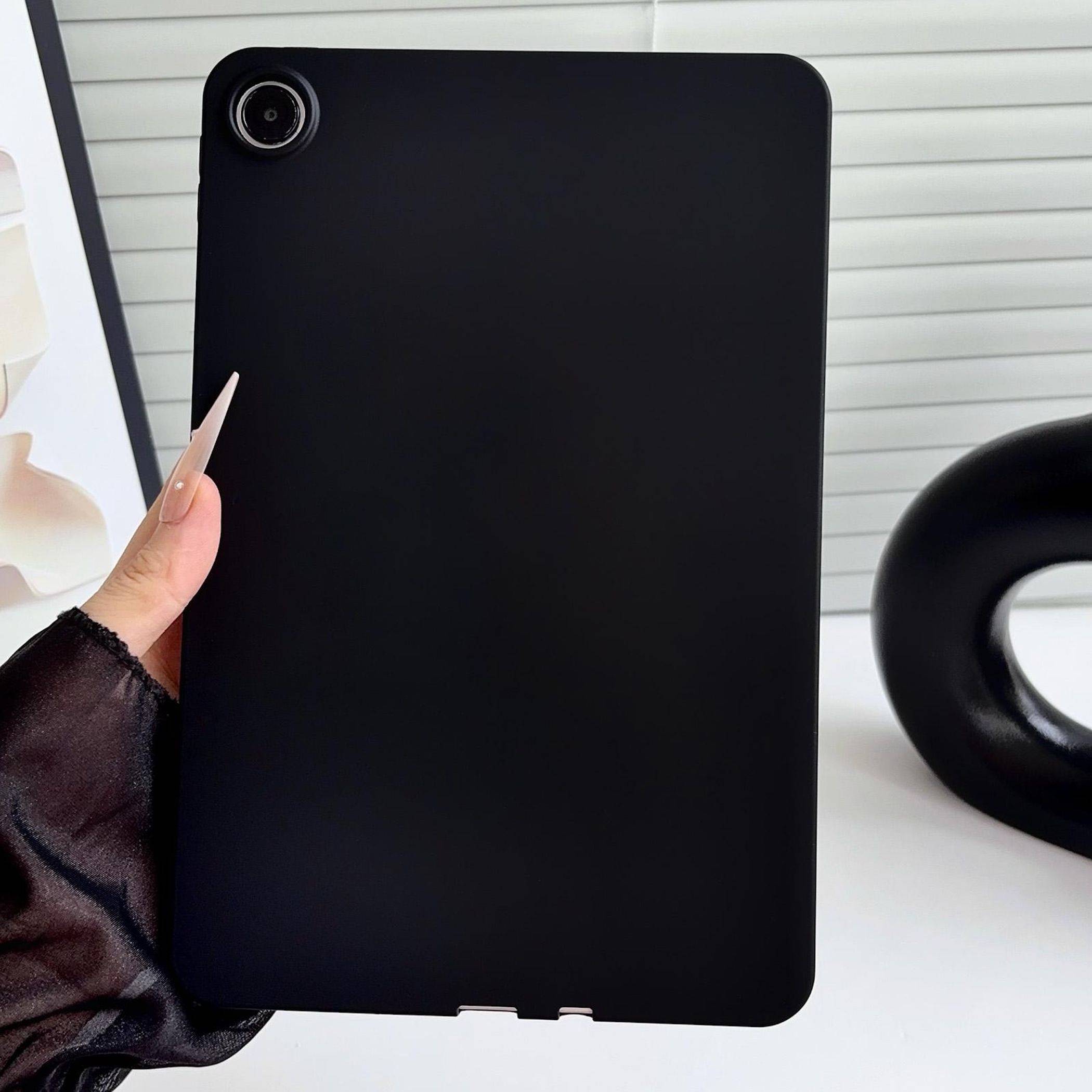 Hand, die ein schwarzes Tablet oder E-Reader mit Rückfahrkamera gegen einen hellen Hintergrund hält.
