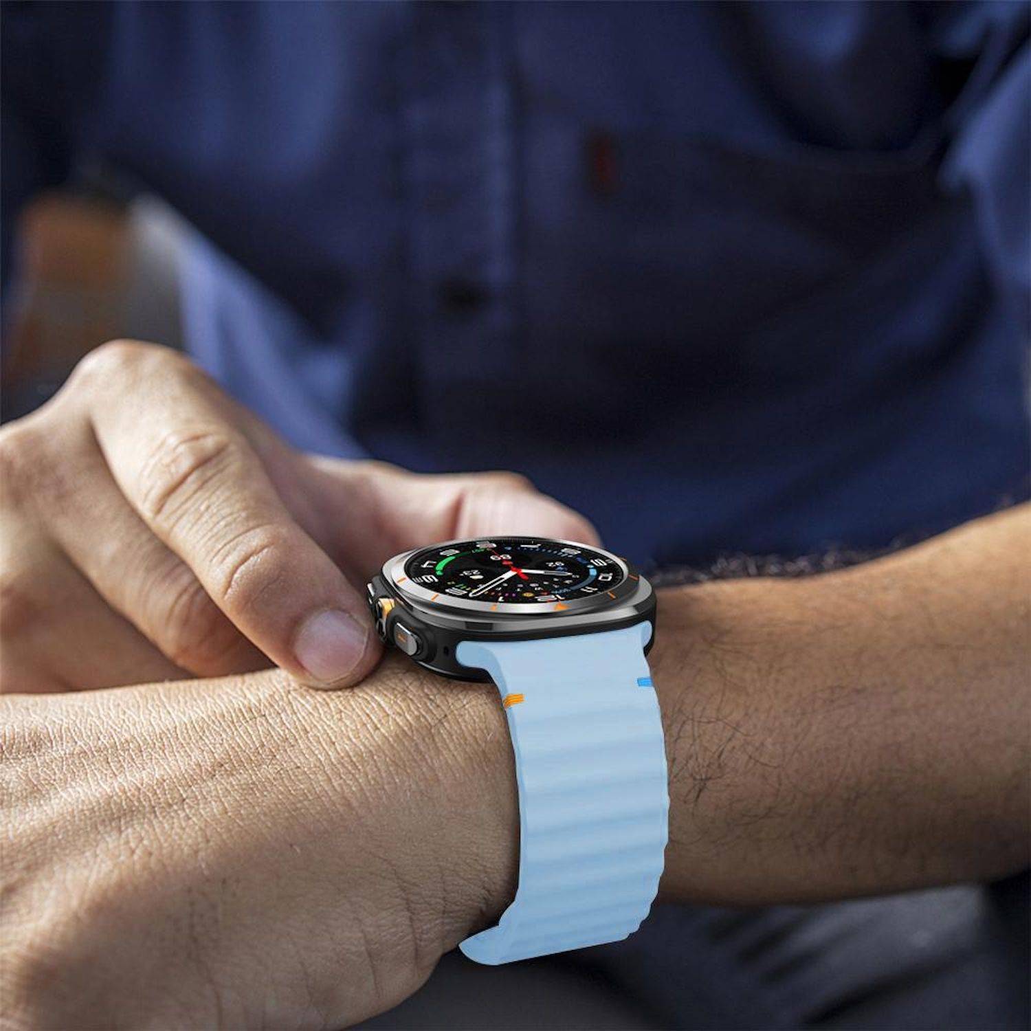 Eine Person stellt eine runde Smartwatch an ihrem Handgelenk ein, gezeigt mit einem hellblauen Armband und einem Zifferblatt im Analogstil.