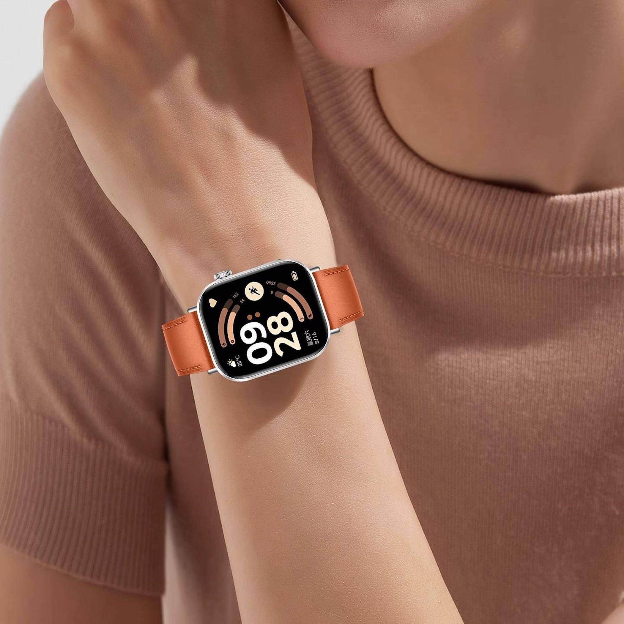 Nahaufnahme eines Handgelenks mit einer quadratischen Smartwatch mit orangefarbenem Armband, die ein digitales Display mit der Uhrzeit 09:28 zeigt.