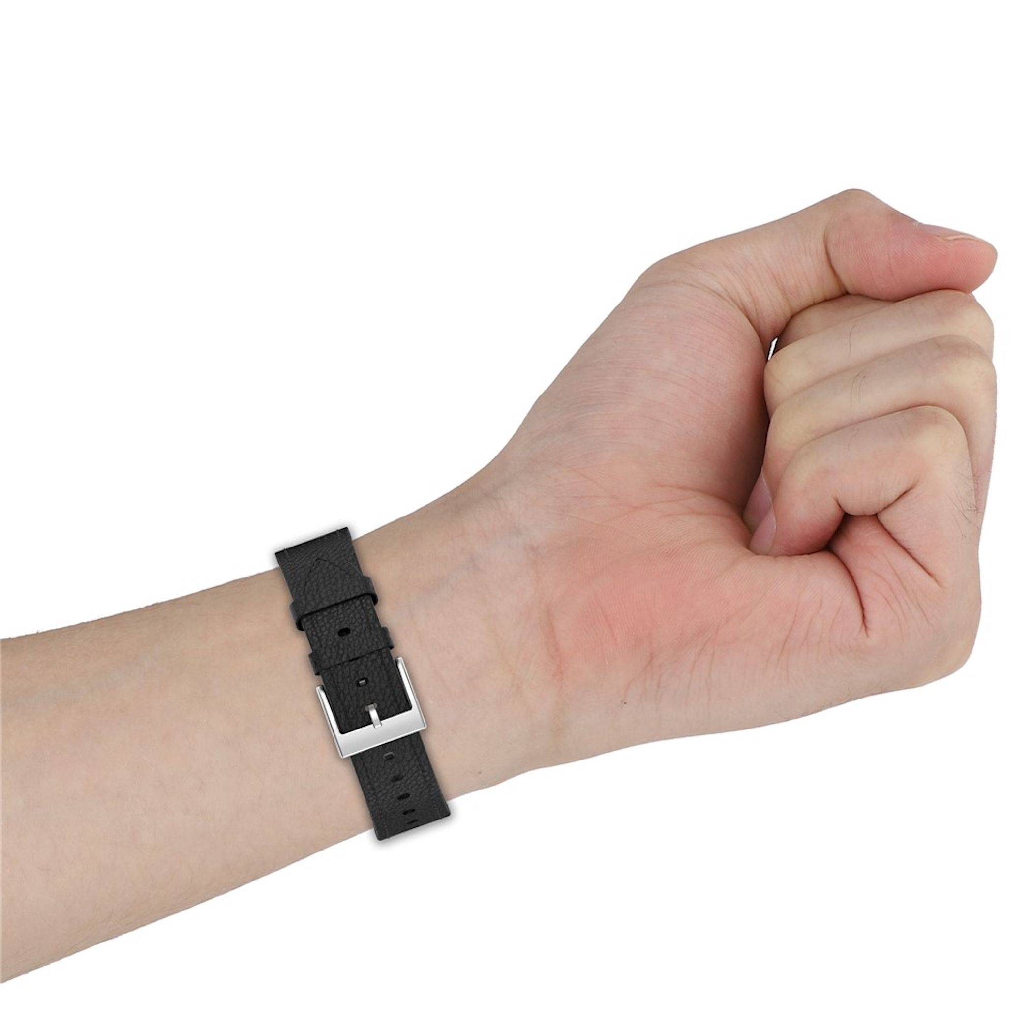 Nahaufnahme einer geballten Hand, die ein schwarzes Armband mit einer silbernen Schnalle auf weißem Hintergrund trägt.