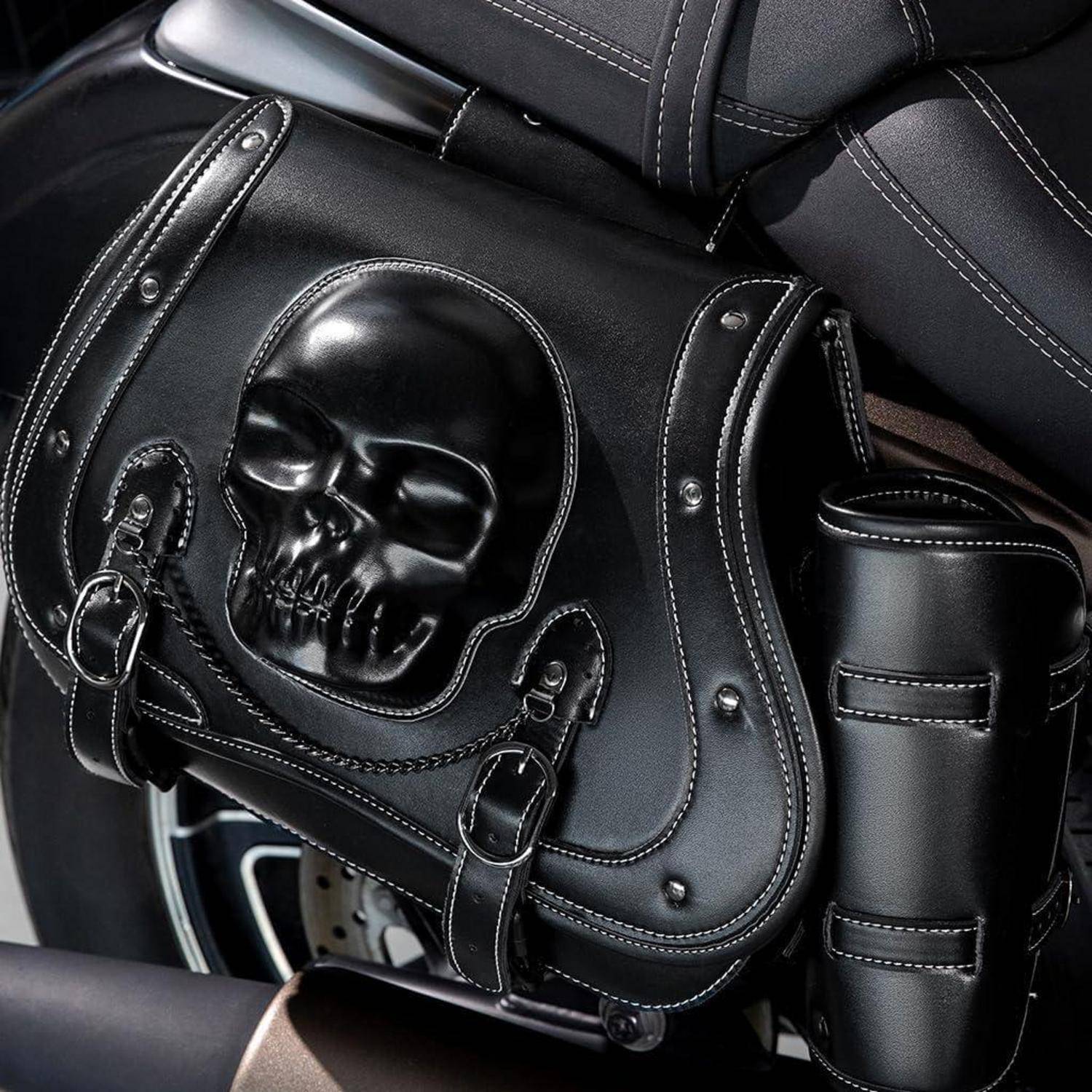 Schwarze Ledermotorrad-Satteltasche mit erhabener Totenkopfdesign und verchromten Schnallen neben dem Sitz montiert.