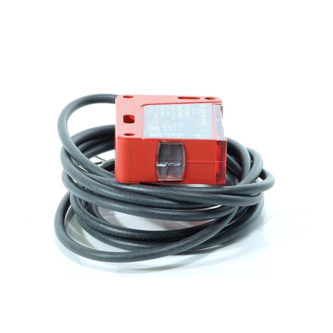 Roter rechteckiger Sensor mit aufgewickeltem grauem Kabel, isoliert auf weißem Hintergrund.