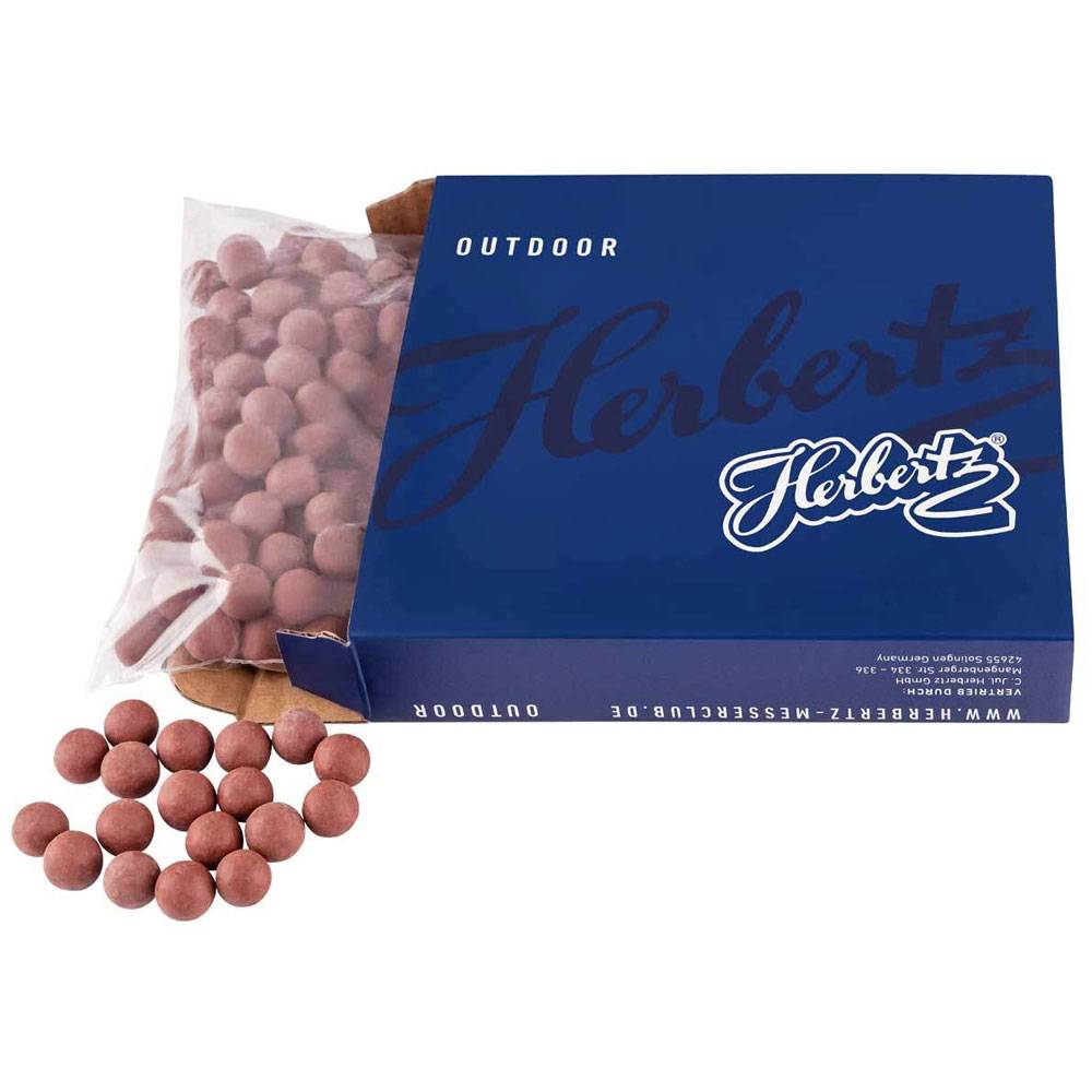 Blue Herberts 'Outdoor' Box mit kleinen braunen Bonbons, von denen einige verstreut sind, und eine durchsichtige Tüte im Inneren sichtbar.