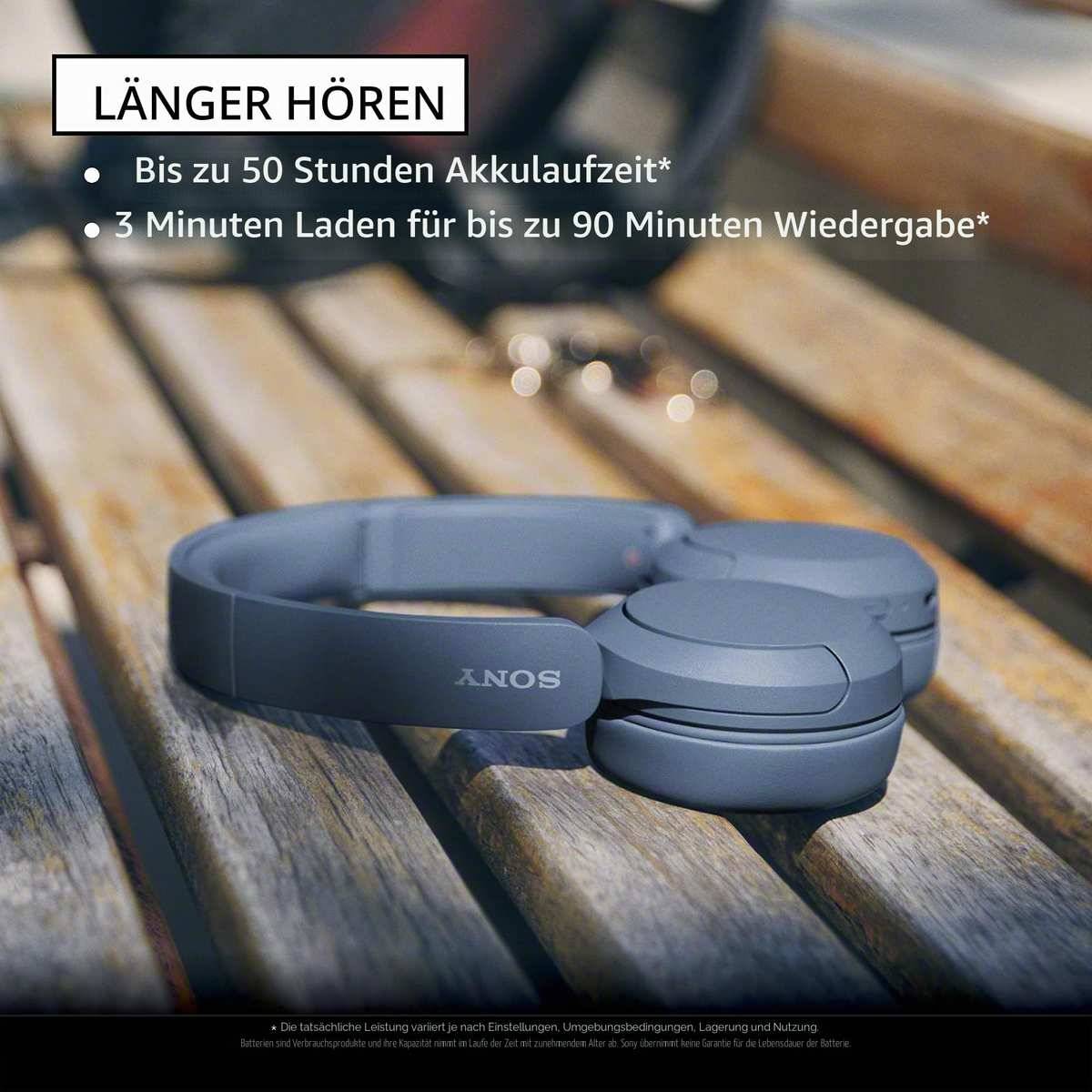 # Sony Kopfhörer auf einer Holzbank mit deutschem Werbtext: 'LÄNGER HÖREN' und Aufzählungspunkte für bis zu 50 Stunden Akkulaufzeit und 3 Minuten Laden für 90 Minuten Wiedergabe.