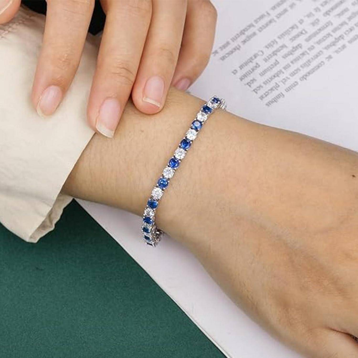 Nahaufnahme einer Hand, die ein blau-silbernes Edelsteinarmband am Handgelenk trägt.