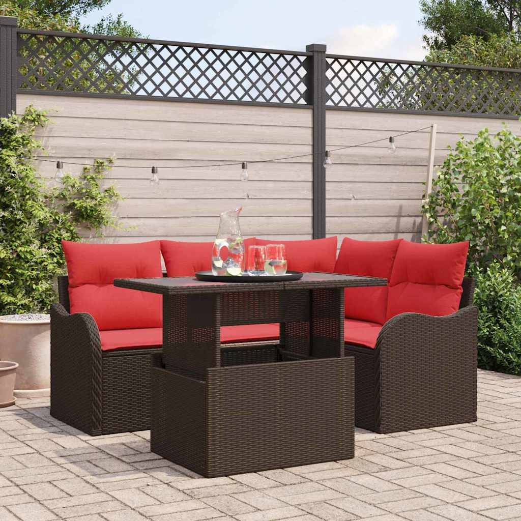 Esszimmergarnitur für den Außenbereich mit rot gepolsterten Eckstühlen um einen dunkelbraunen Korbflechttisch angeordnet, dargestellt auf einer gepflasterten Terrasse im Hinterhof.