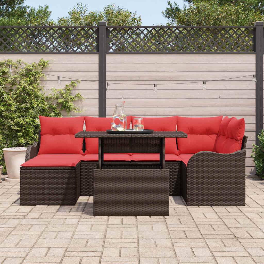 Outdoor-Sitzgarnitur auf der Terrasse mit roten Kissen und dunklem Rattansofa, Hocker und Tisch mit Getränken vor einem Zaun und Lichterketten.
