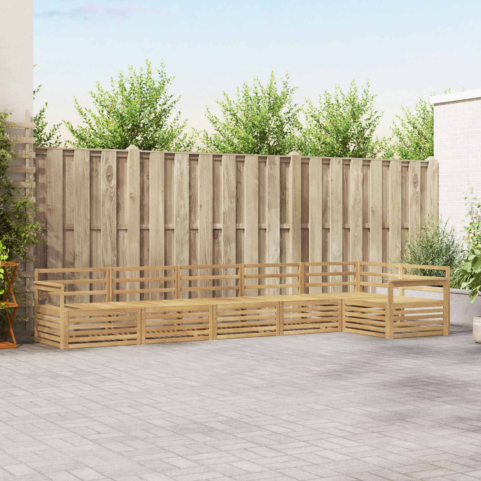 Holzbank mit Eckenaufstellung und Lattenrückenlehne sowie Lattenseiten auf einem gepflasterten Terrassenbereich, aufgestellt vor einem hohen Holzzaun und Grünflächenbepflanzung.