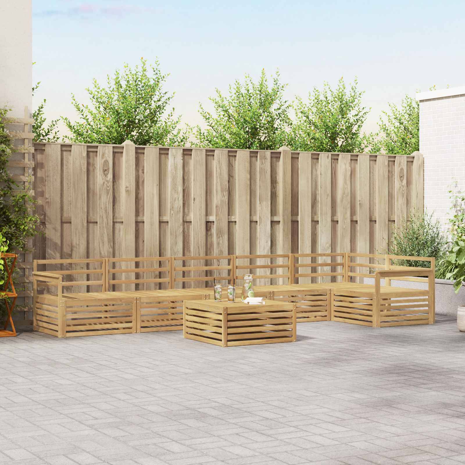 Outdoor-Sofa-Set aus Holz mit niedrigem Couchtisch auf einer gepflasterten Terrasse neben einem hohen Zaun und Gartenbegrünung
