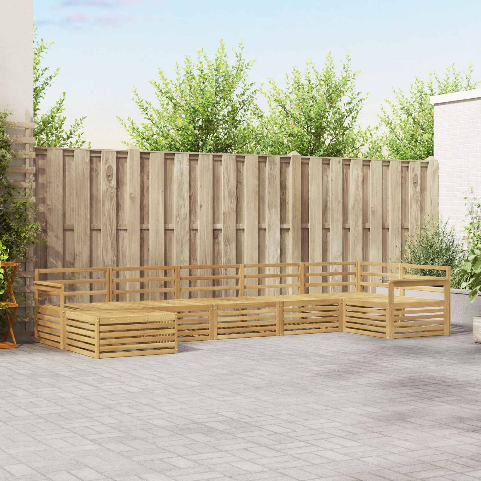Holzgarnitur im L-Format für den Außenbereich, die auf einer Terrasse neben einem hohen Zaun angeordnet ist, mit Blumenkübeln und Grünpflanzen im Hintergrund.