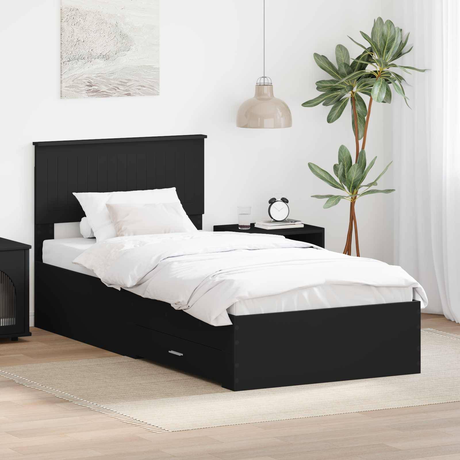 Minimalistisches Schlafzimmer mit einem schwarzen Einzelbett, bezogen mit weißer Bettwäsche, einem Nachttisch und einer Lampe, einer Topfpflanze und hellem Holzfußboden.