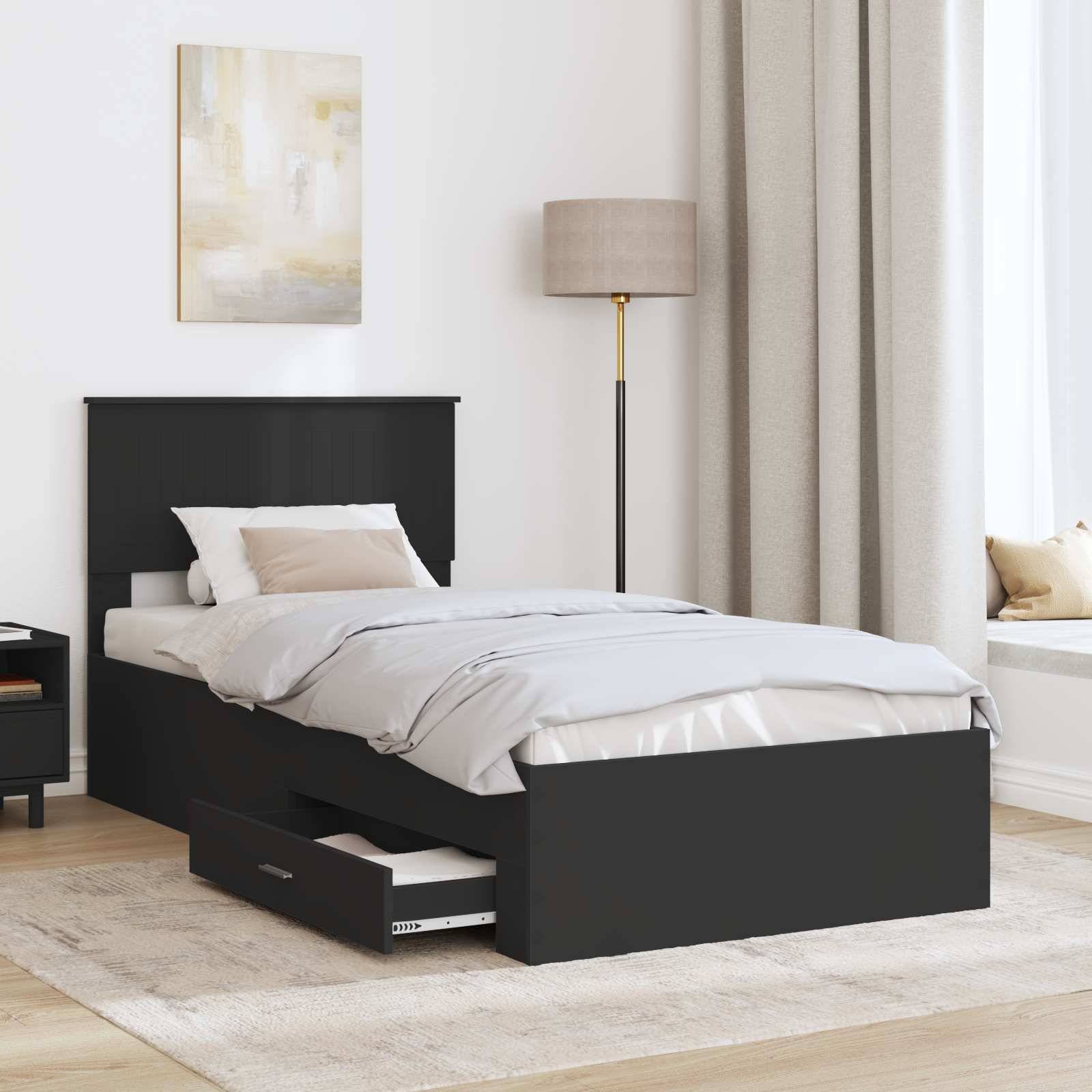 Modernes Schlafzimmer mit einem schwarzen Einzelbett und ausziehbarem Stauraum, weißer Bettwäsche, Stehleuchte, Wandkunst und neutralen Vorhängen.