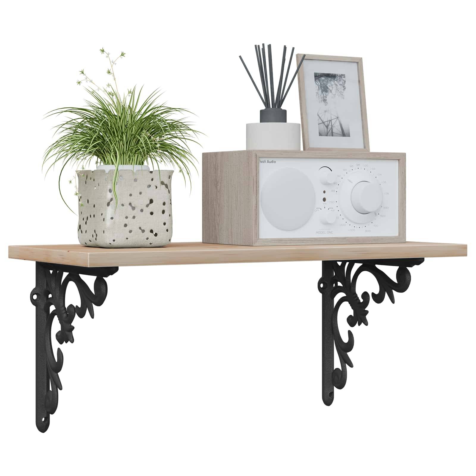 Wandregal mit verziertem schwarzem Halterungsset, das einen Blumentopf, ein kleines Radio, einen Raumduftspender und ein gerahmtes Foto hält.