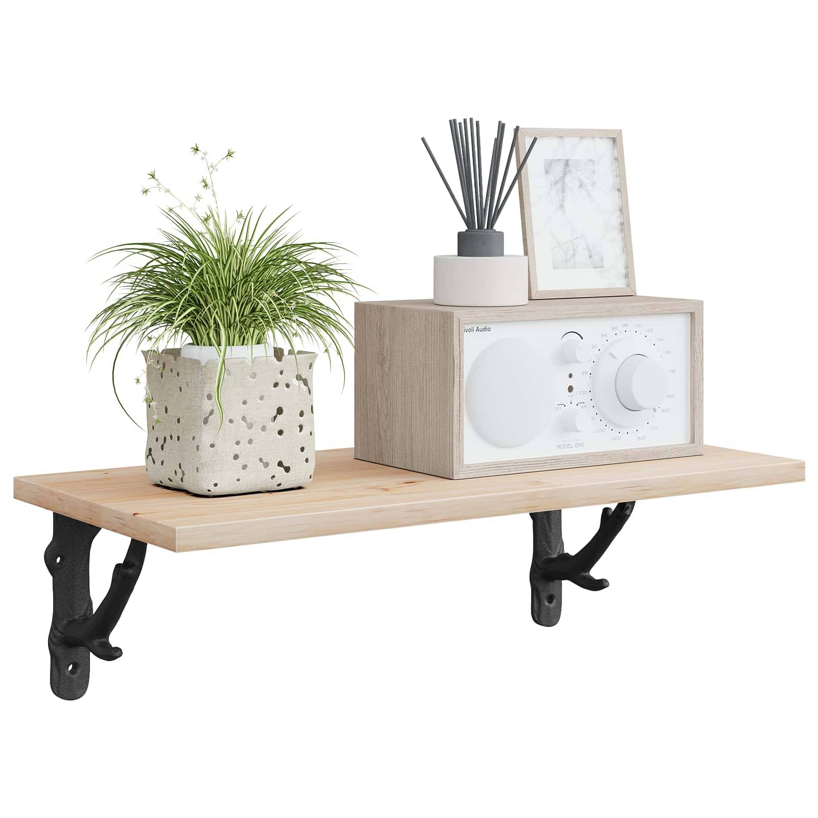 Wandmontiertes Holzregal mit schwarzen Halterungen, auf dem eine gefleckte Topfpflanze, ein Raumduft-Diffuser und ein gerahmtes Bild über einem kleinen weißen Gerät oder einer weißen Box stehen.