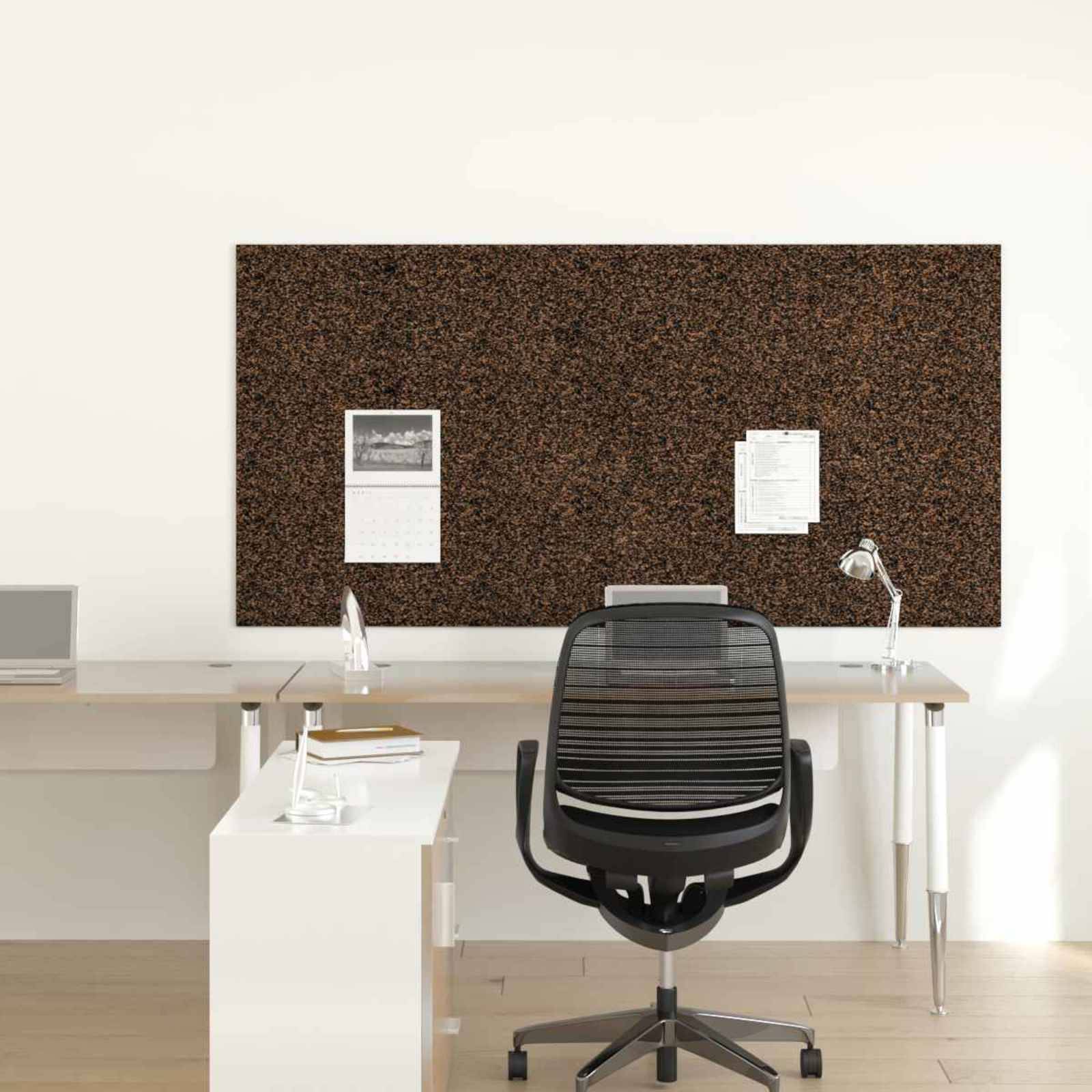 Leerer moderner Büroarbeitsplatz mit schwarzem Drehstuhl an einem Schreibtisch, Korkpinnwand, Lampe und an der Wand angehefteten Papieren.