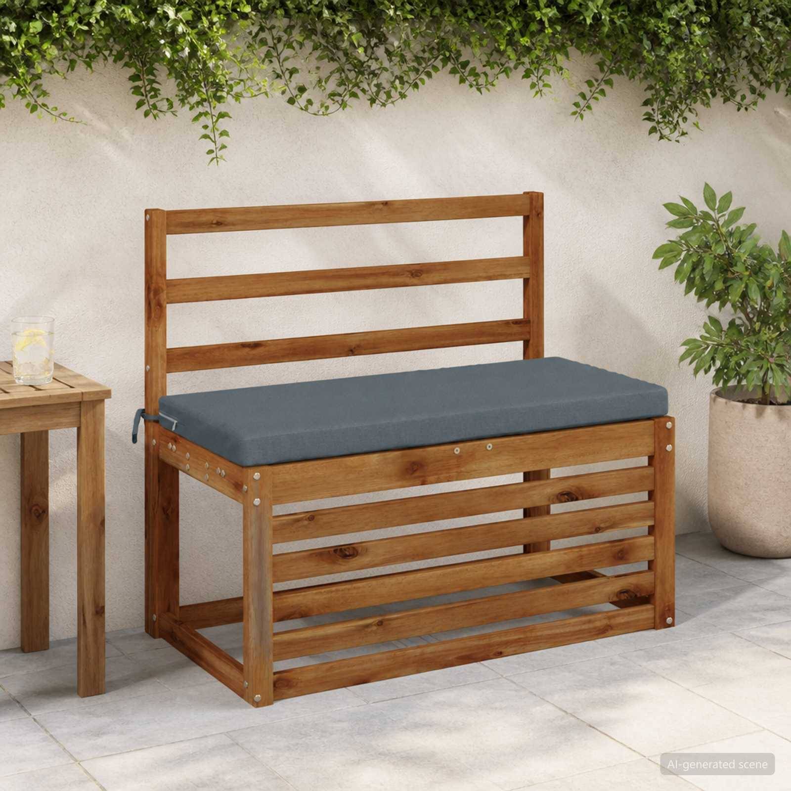 Holzgartenbank mit grauem Kissen auf einer Terrasse neben einem kleinen Tisch und einer Topfpflanze.