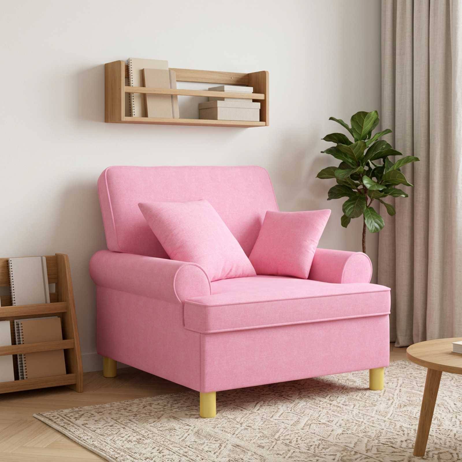 Rosa gepolsterter Sessel mit zwei passenden Kissen in einem modernen Wohnzimmer, neben einer Pflanze, Wandregalen und einem runden Tisch.