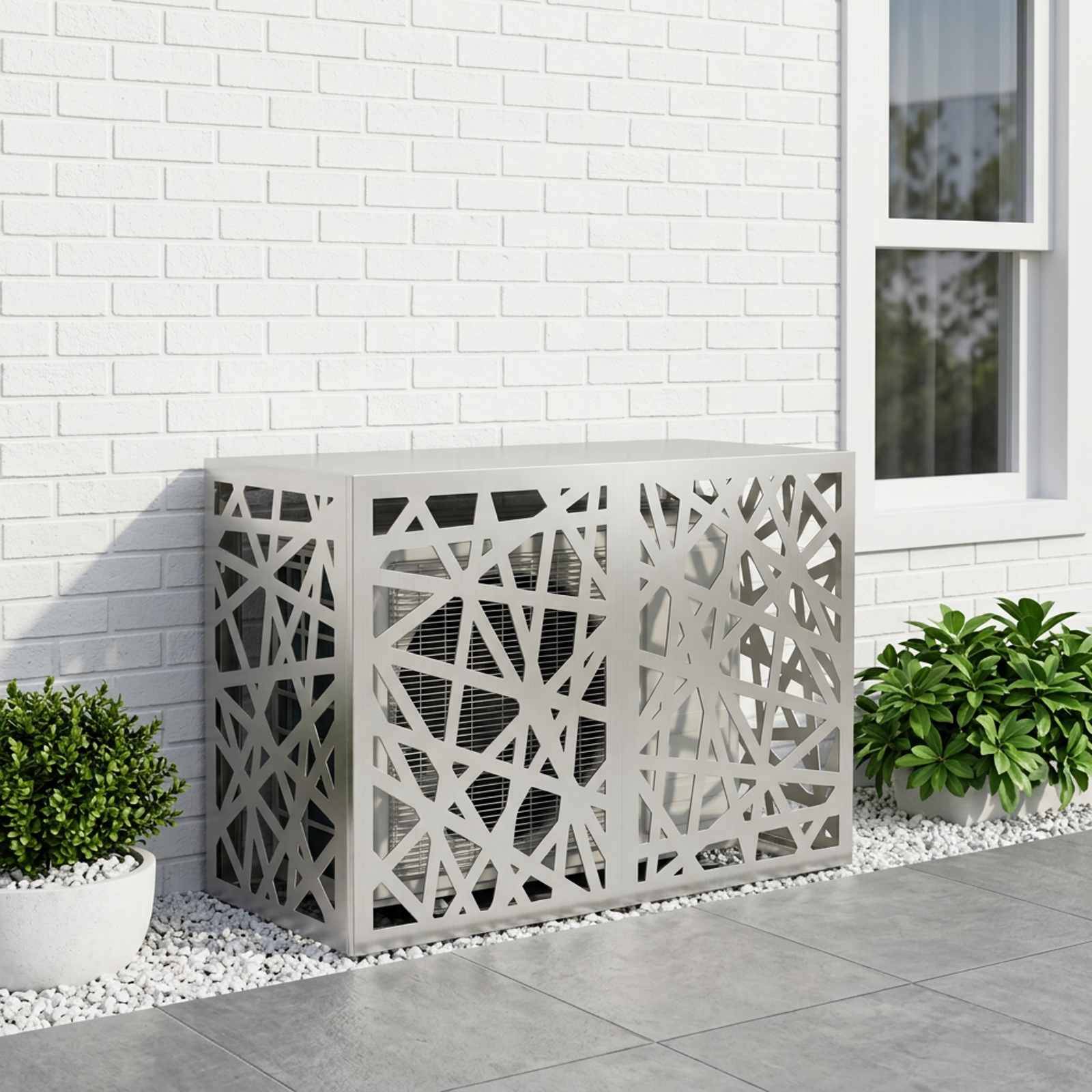 Dekorative Klimaanlage-Außenverkleidung mit geometrischem Ausschnittdesign neben einem weißen Ziegelsteinhaus und Fenster, flankiert von Topfbüschen.