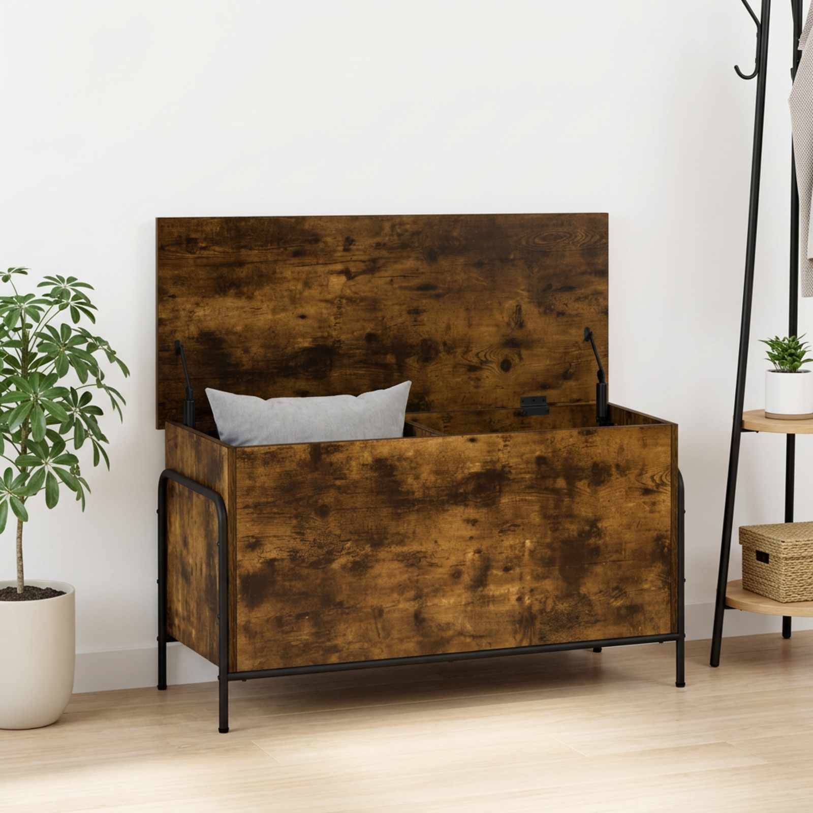 Rustikales Holz-Speicherbett mit offener Deckelklappe, schwarzem Metallrahmen und einem Kissen, dargestellt in einem minimalistischen Raum mit Pflanzen.