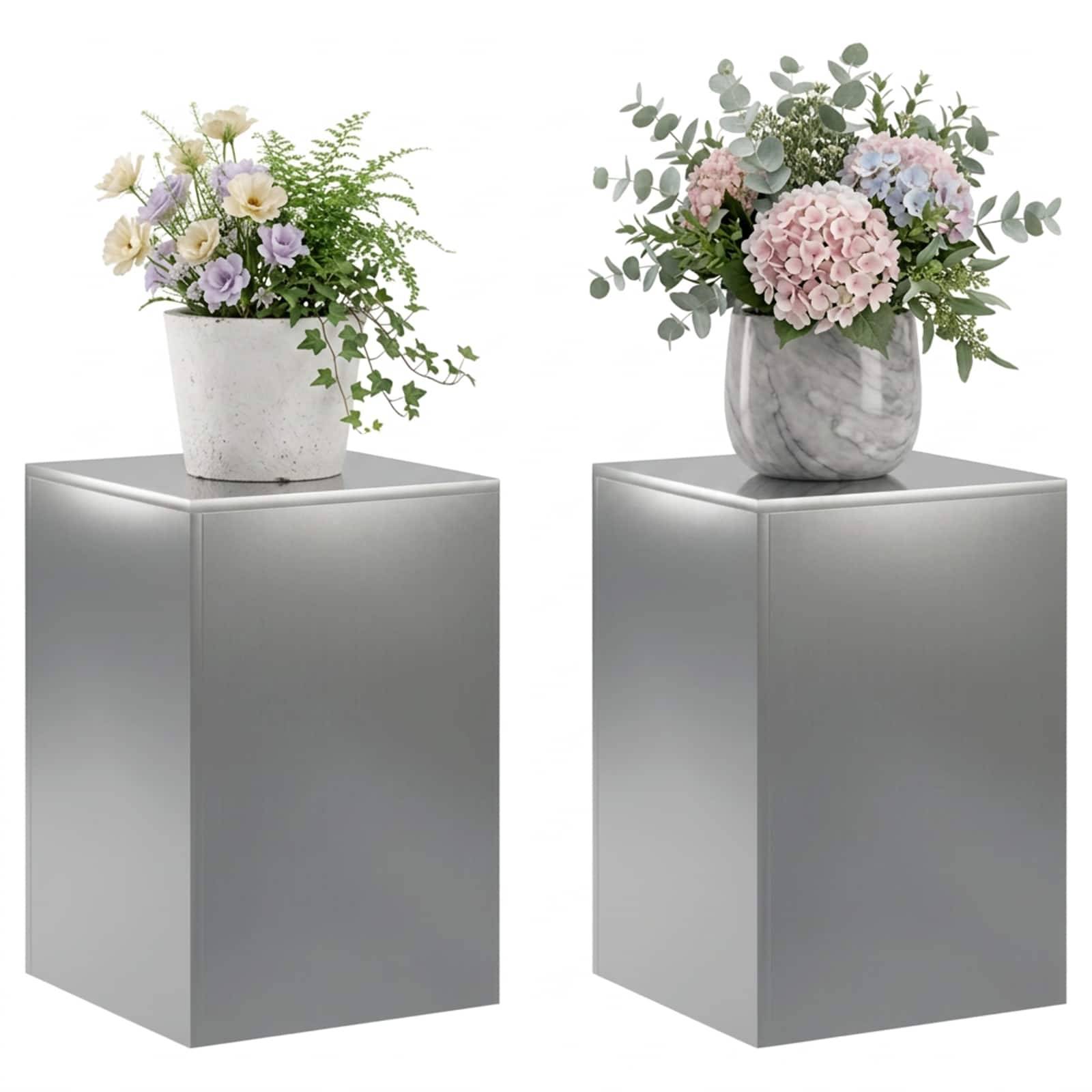 Zwei Blumenarrangements in weißen und grauen Vasen stehen auf separaten silbernen Sockeln vor weißem Hintergrund.