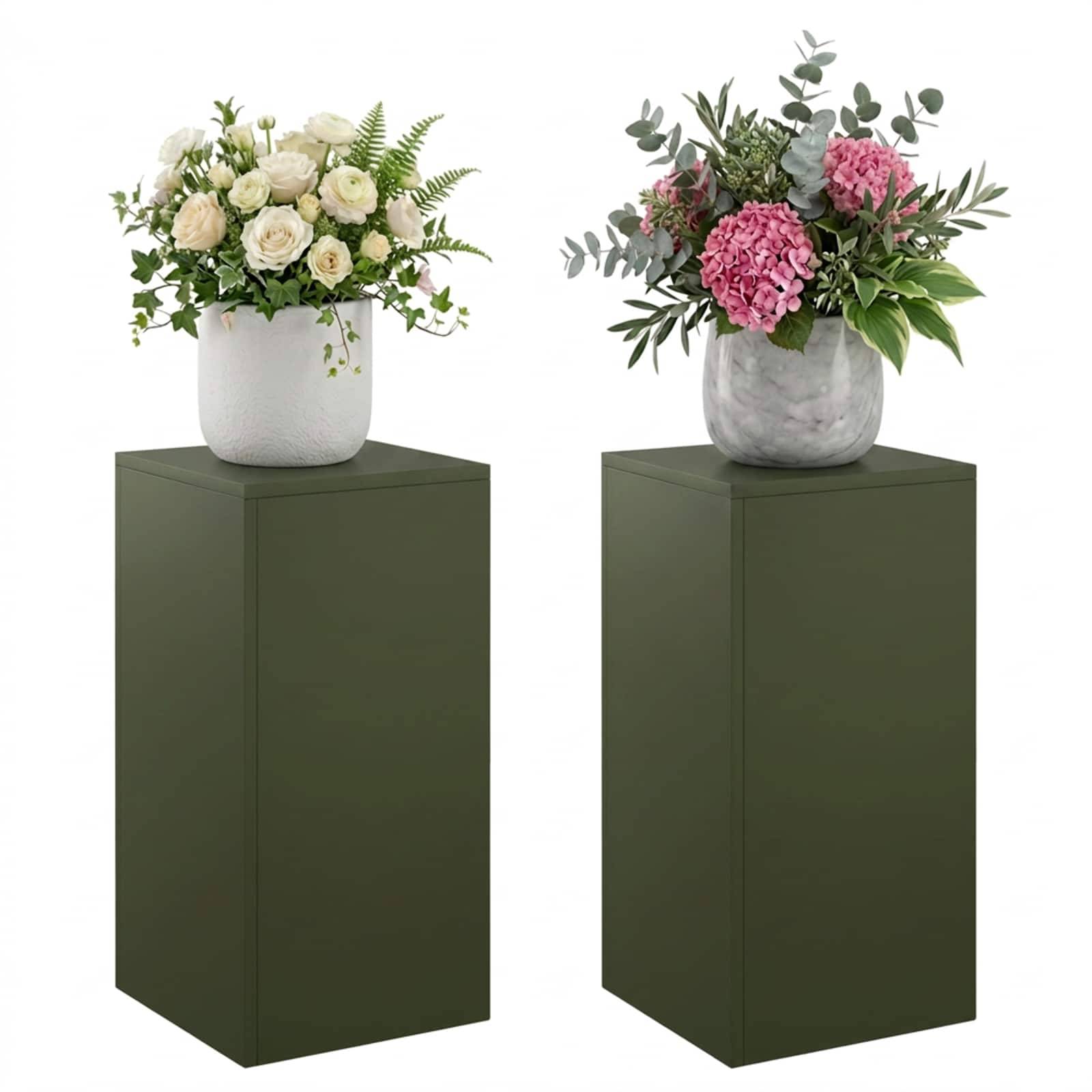 Zwei Blumenarrangements in weißen Vasen stehen auf hohen dunkelgrünen Sockeln vor weißem Hintergrund, eines mit weißen Rosen und eines mit rosa Hortensien.
