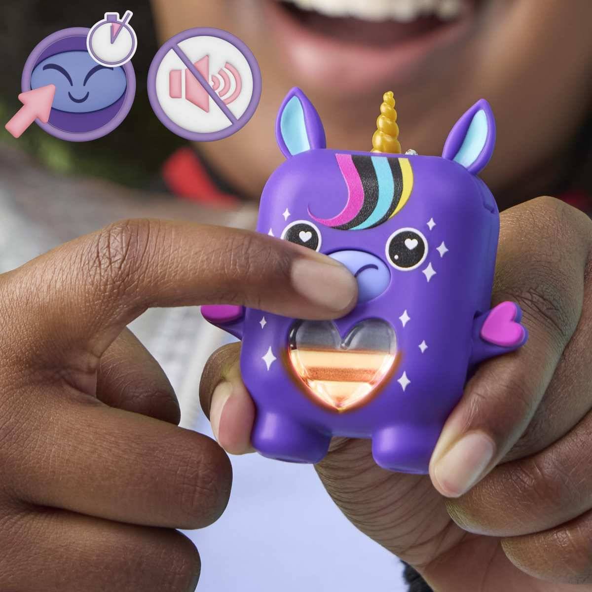 Ein Kind drückt auf ein violettes Einhorn-Fidget-Spielzeug mit leuchtenden Herz und Zubehör, was auf ein knopfaktiviertes sensorisches Spielzeug hindeutet.