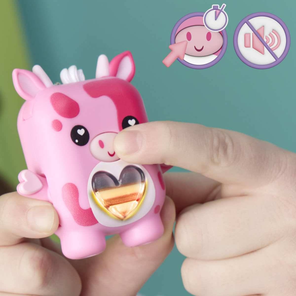 Hände drücken ein rosa kuhhförmiges Druckspielzeug, das eine herzförmige Leuchtfunktion auf seinem Bauch zeigt.