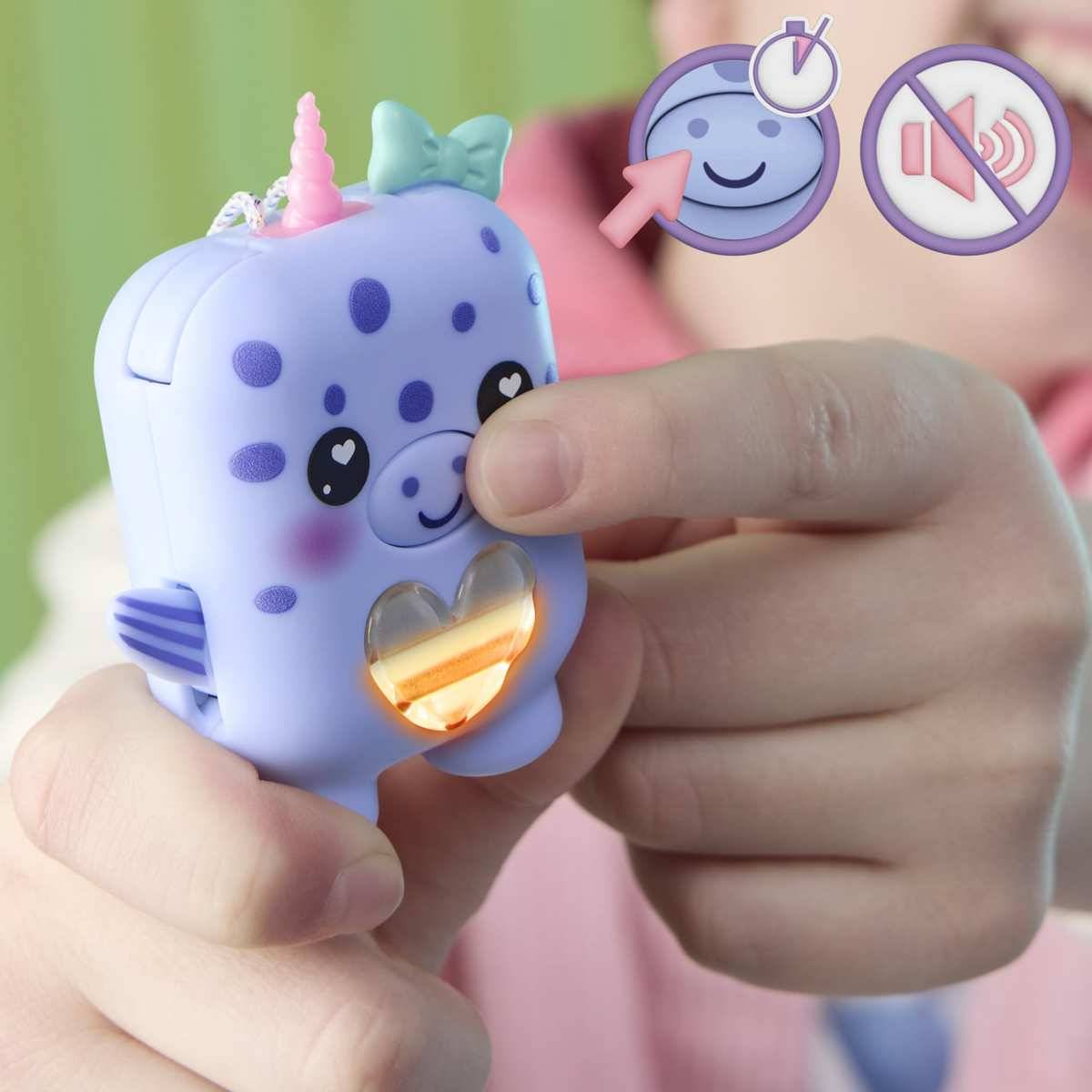 Kind hält ein leuchtend violettes Einhorn-Spielzeug mit leuchtendem Herz; Symbole zeigen Timer und stummen Ton, was auf ein leuchtendEs, zeitgesteuertes Spielzeug hinweist.