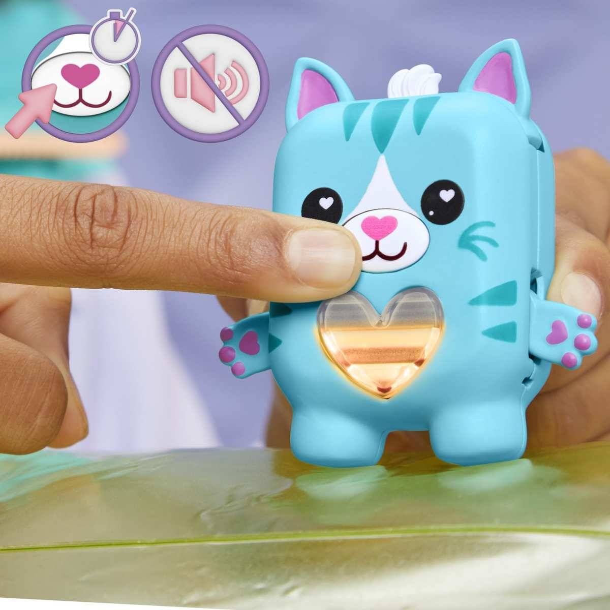 Ein Finger drückt auf eine blaue Spielzeugkatzenfigur und aktiviert damit ihr leuchtendes herzförmiges Brustfeld; Symbole zeigen an, die Nase zu berühren und den Soundknopf zu vermeiden.