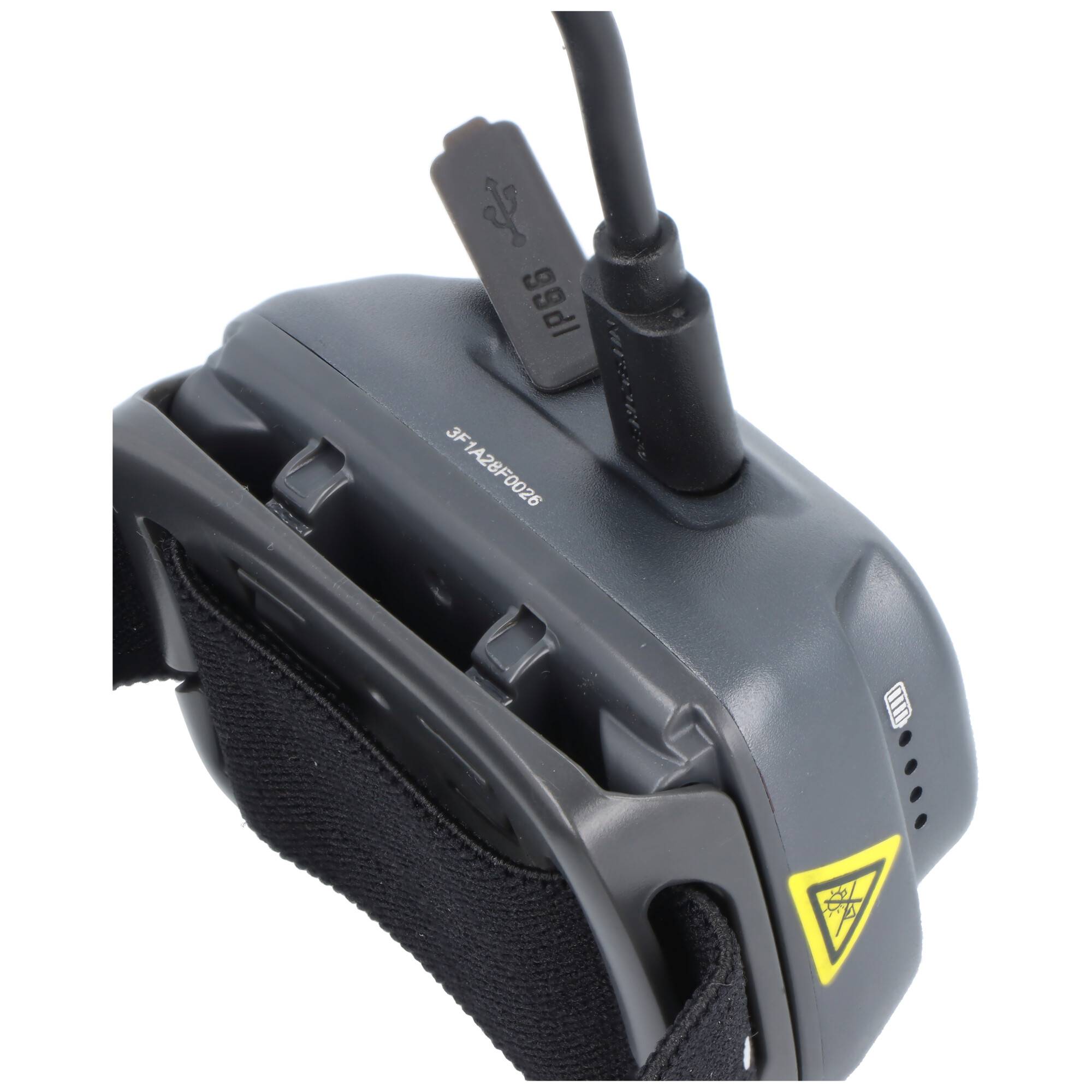 Nahaufnahme eines schwarzen tragbaren elektronischen Geräts mit angeschlossenem USB-Kabel und Riemen, das ein gelbes Warnsymbol und kleine Anzeigelöcher zeigt.