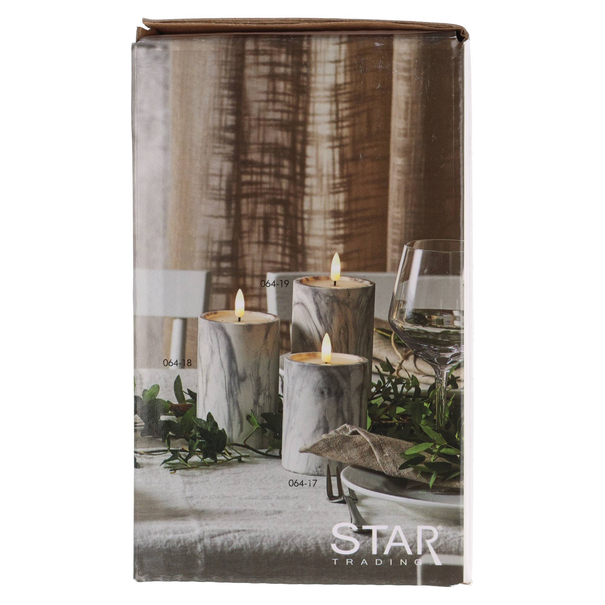 Verpackung für STAR TRADING Kerzen mit drei brennenden Säulenkerzen mit Marmermuster auf einem Tisch mit Grünpflanzen und Glaswaren.
