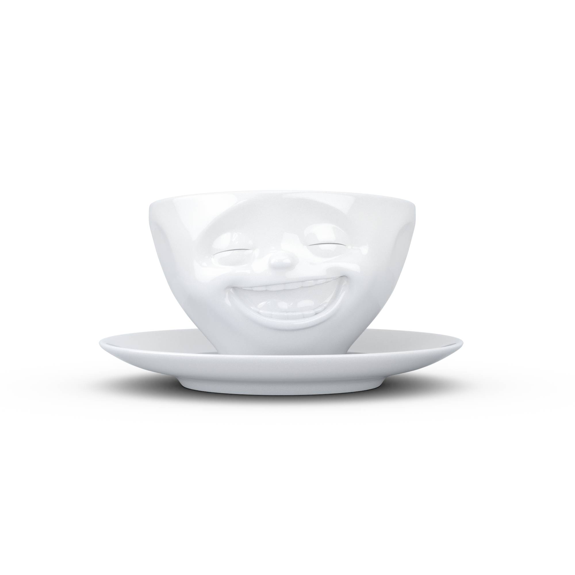 Weiße Teetasse mit einem lächelnden Gesicht und geschlossenen Augen, die auf einer Untertasse vor einem schlichten weißen Hintergrund ruht.