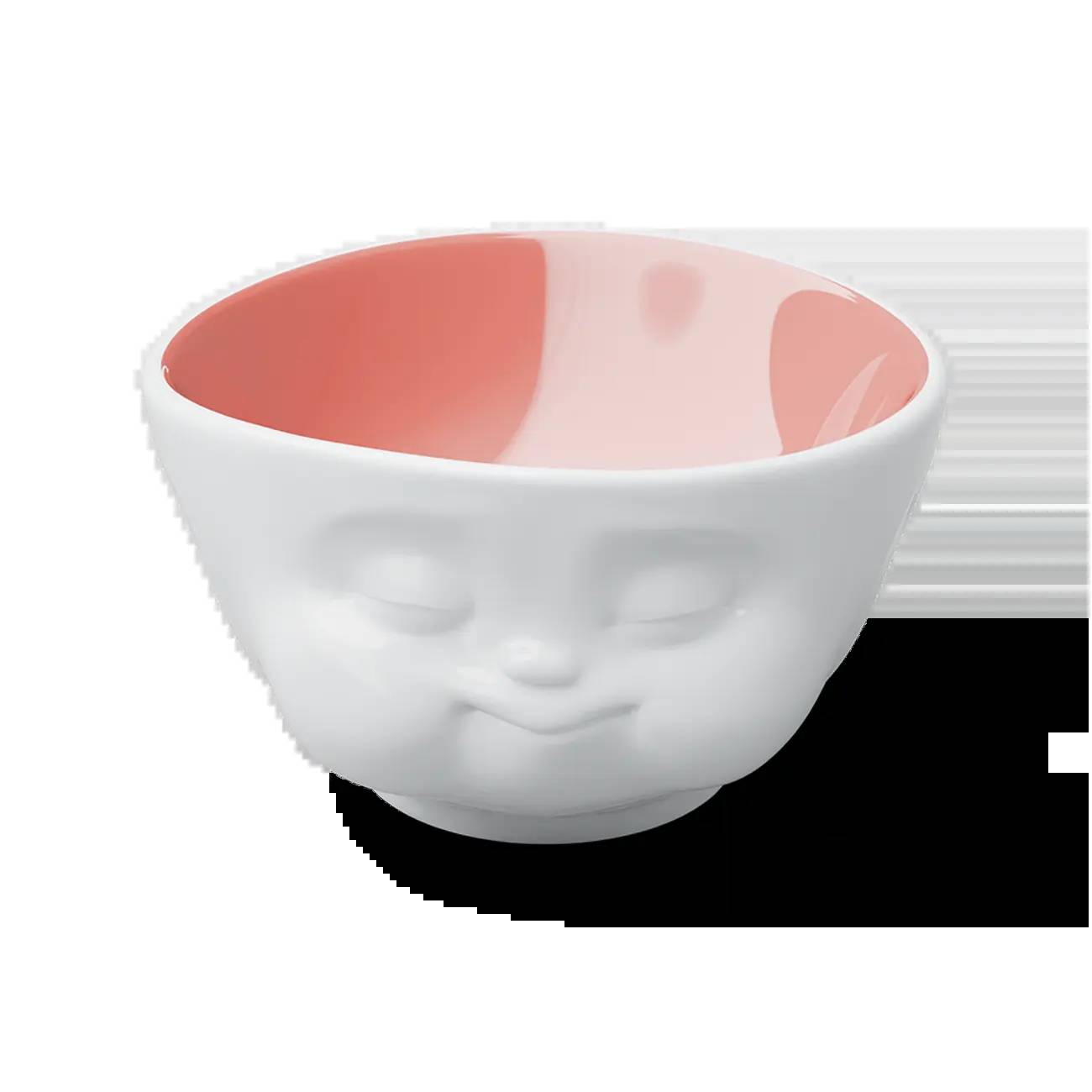 Weiße Keramikschale mit einem skulptierten lächelnden Gesicht auf der Außenseite und glänzendem rosa Innenbereich, vor schwarzem Hintergrund gezeigt.