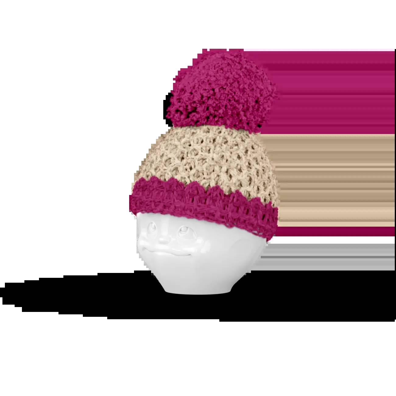 Weißer Schaufensterpuppenkopf, der auf schwarzem Hintergrund eine gestrickte rosa und beige Pudelmütze mit Bommel trägt.