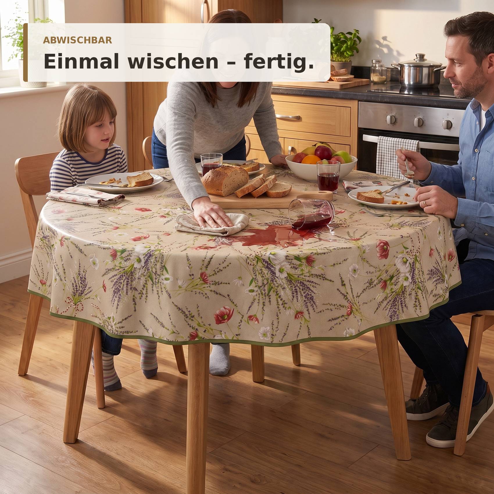 Familie sitzt an einem Küchentisch; eine Person wischt die gemusterte Tischdecke mit einem Tuch ab. Der Text sagt „ABWISCHBAR" und „Einmal wischen - fertig."