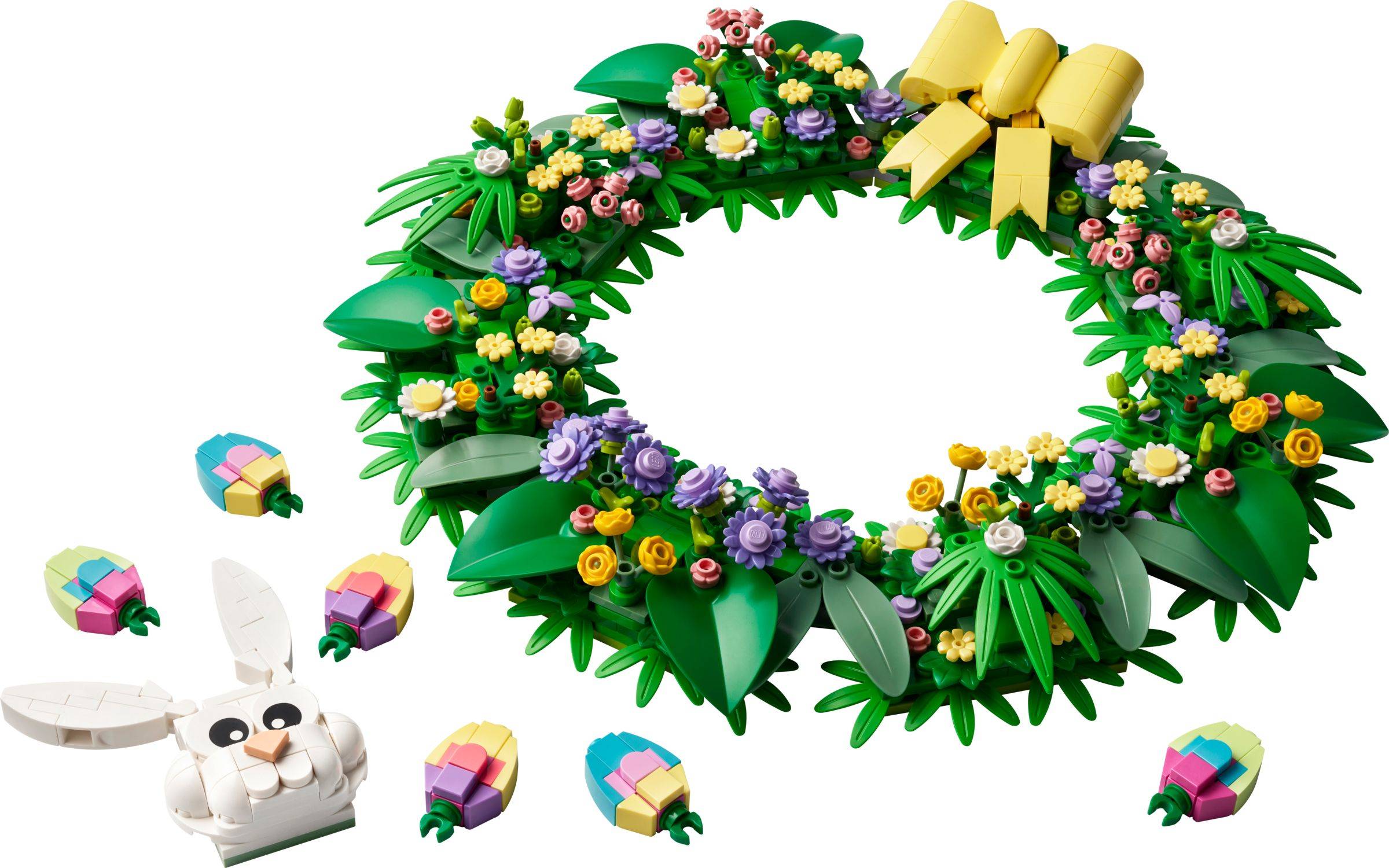 LEGO-artiger Blumenkranz mit einer gelben Schleife, umgeben von kleinen pastellfarbenen Geschenkstücken und einem weißen Kaninchenkopf unten links.