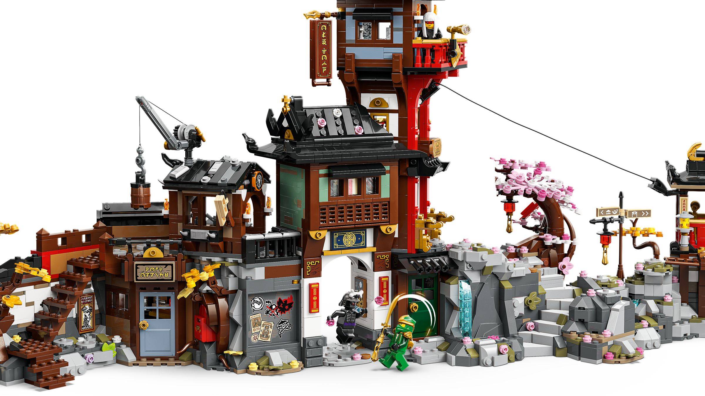 Eine LEGO-Ninja-Festung mit Türmen, Toren, Brücken und Minifiguren in einer felsigen Tempellandschaft mit Kirschblütenbäumen.
