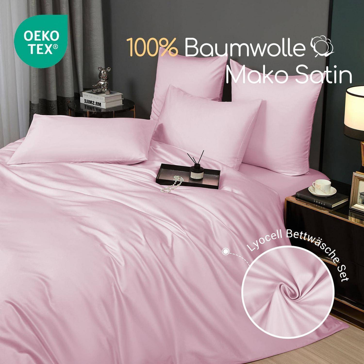 Rosafarbene Satin-Bettwäsche-Garnitur auf einem gemachten Bett mit Kissen, gekennzeichnet mit „100% Baumwolle Mako Satin" und „Lyocell Bettwäsche-Set"", mit OEKO-TEX-Siegel.