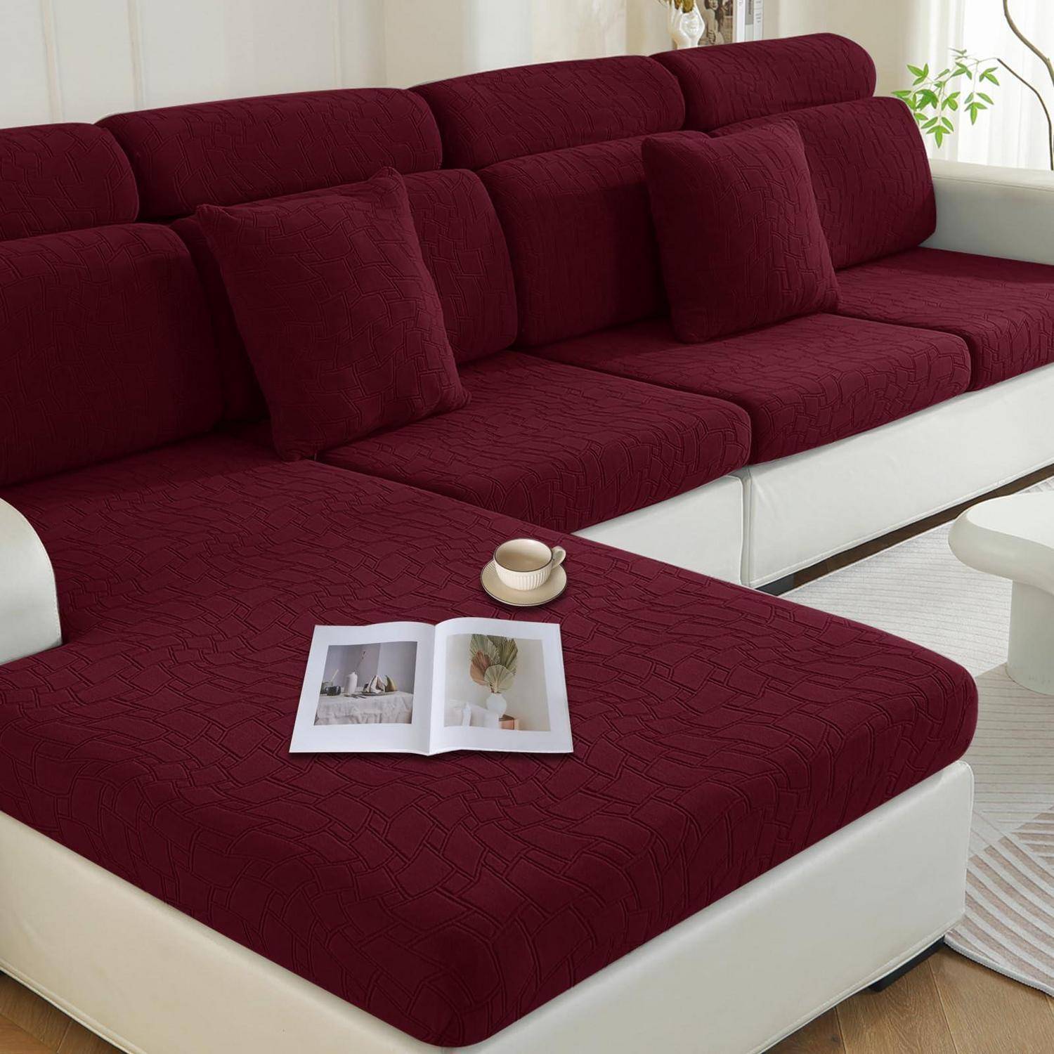Bordaux- und weißes Ecksofa mit Liege, ein offenes Magazin und eine Tasse auf dem Sitz in einem hellen Wohnzimmer.
